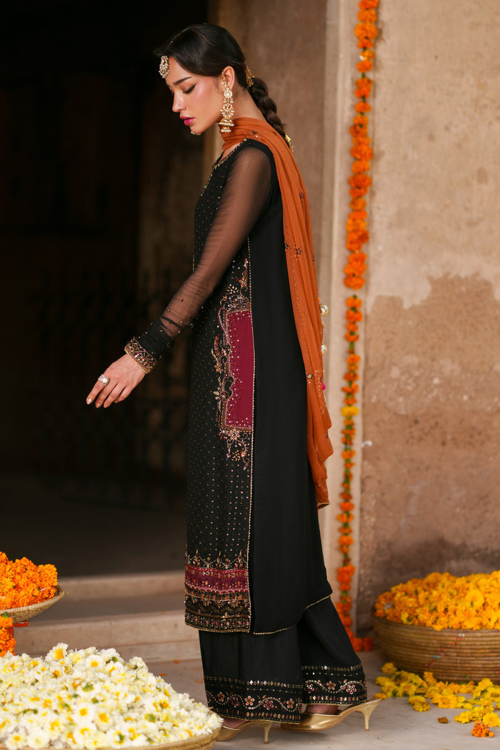Side view of Zarim black crinkle semi formal outfit featuring flowing sleeves, orange contrast dupatta and festive embellishment work