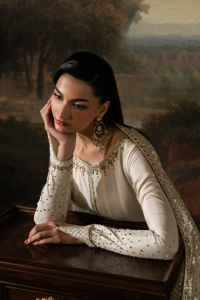 Close portrait of Zarsanga highlighting the boat neckline, Adda work and detailed extended sleeves of the off-white frock.