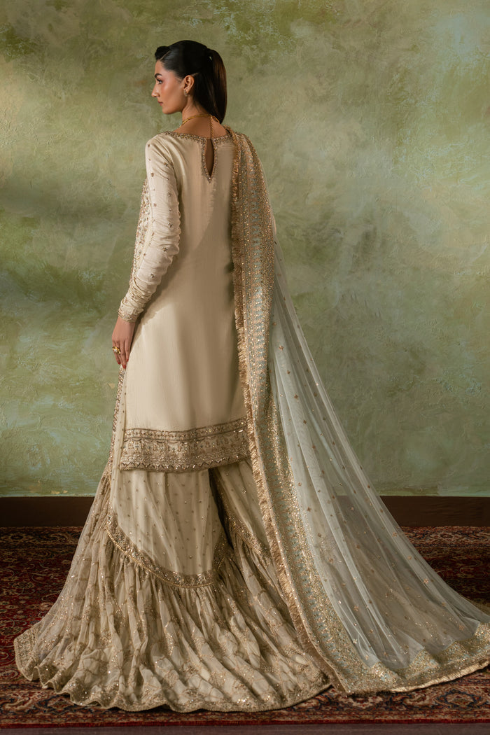 Back view of Zemira Nikkah dress showing smooth fall of raw silk shirt and wide farshi gharara flare with net dupatta trail, elegant ready made bridal formal outfit.